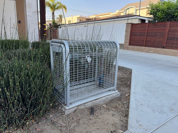A backflow cage in San Diego covers backflow equipment next to residential housing units.