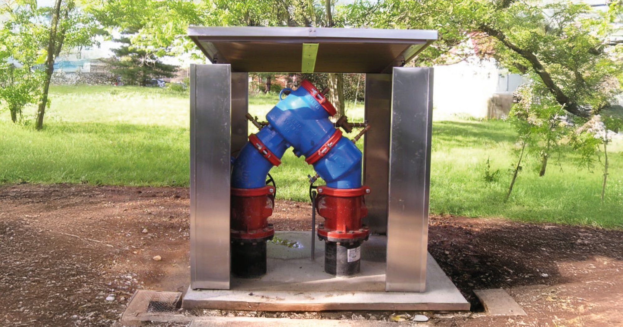 A backflow enclosure with removable side panels showing an n-shaped backflow assembly in saves space in an above-ground aluminum enclosure