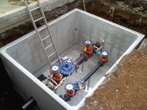 A backflow preventer in a vault, an example of "utility vault mentality," which is both costly and risks physical harm.